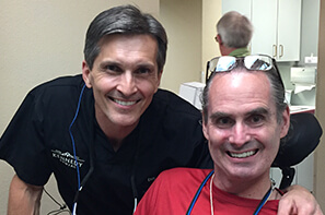 Male volunteer dentist with male patient in red shirt