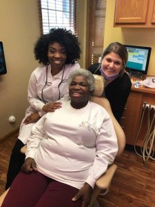 Dr. Sarah Thompson and her assistant smile with Karen for DDS. 